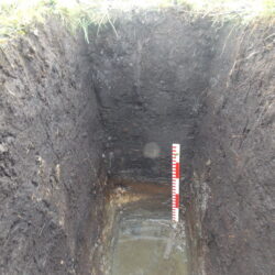 A hand-dug test pit to investigate the deposit sequence within a small, low-lying depression (scale = 0.5m). © Copyright ARS Ltd