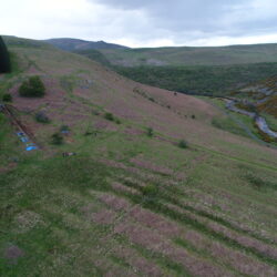 A view of the site within the Breamish Valley. Note the trench running down through the terraces and pointing towards later medieval ridge and furrow remains.