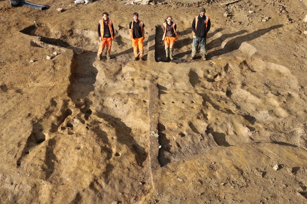 A high angle shot of ARS Staff standing in the fully excavated stone and timber building © Copyright ARS Ltd 2022