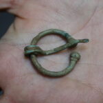 For today's #FindsFriday, we have this beautiful Roman Penannular brooch! This style of brooch dates approximately to the 1st - 2nd centuries AD and this type is most notable in the north of England, especially Yorkshire/Humberside. Our example is in excellent condition, with the pin still attached. It would have been worn with the pin being pushed through the folds of the fabric and the free end of the pin passing through the gap in the ring. The pin would then be rotated around by about 90 degrees so that it is held down by the frame. © Copyright ARS Ltd 2022
