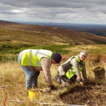 Further excavation of a magnetometry anomaly at the Irontongue by TAS volunteers Carolanne King and Dee Whitmore overlooking Manchester to the west © Copyright Tameside Archaeological Society 2022