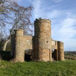 In this week’s #BuildingKnowledge we're looking at the Grade II Listed folly on the grounds of Nercwys Hall, Flintshire, Wales. The folly dates to the late 18th or early 19th century, with the Hall constructed in the early 18th century in the Elizabethan style. While there had been important structures within the landscape for country houses in the previous centuries, it wasn’t until the 18th century that we started to see the construction of the weird and wonderful folly. The name is apt, given the extravagance and impractical use of these structures. They were costly and grand in their designs, representing important and eye-catching fixtures within the designed landscape of country houses. They were often built on distant hillsides, giving the owner a clearer sense of the vast range of their lands. With the Picturesque movement in the later 18th century, came an increasing range of follies in the form of sham castles, as we see with this structure. The folly has been constructed in sandstone with a central tower flanked by shorter towers, with crenelated battlements, and with decorative blind crosses and quatrefoils. © ARS Ltd 2021