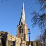 In this week’s #BuildingKnowledge we take a look at the Grade I Listed St Mary and All Saints Parish Church, Chesterfield, with its wonderfully wonky spire. The building originally dates to c.1234, with the present structure predominantly dating from the 14th century, as well as rebuilt sections from the 18th century. The building forms a mixture of Early English, Decorated, and Perpendicular Gothic styles, with 19th century restoration works undertaken by prominent Gothic Revival architect Sir George Gilbert Scott in 1843. The spire was constructed in c.1362, with the reason for its famous twisted shape still debated. One theory suggests that sunlight heating the southern side of the spire had caused the lead to expand at a greater rate than the northern side. Another purports that the plague of the 14th century had resulted in a shortage of skilled craftsmen, with the use of ‘green timber’ and lack of cross-bracing being the reason behind the contortion. Local legend suggests however that the devil had wrapped his tail around the spire, causing it to become crooked! © ARS Ltd 2023