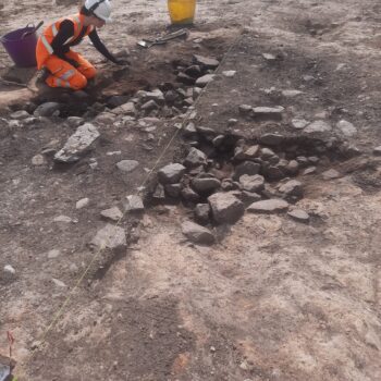 Excavation underway of a large, stone-filled pit. The function of this pit remains unclear, but is similar in form to some that we've excavated on a site in Elgin © ARS Ltd 2025